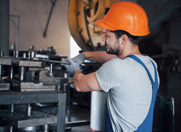 Experienced operator in a hard hat. Metalworking industry concept professional engineer metalworker operating CNC milling machine center in manufacturing workshop