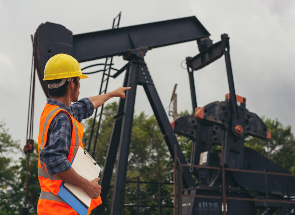 Workers standing and checking beside working oil pumps.